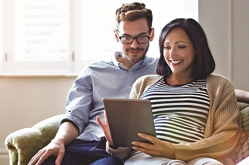 A pregnant woman and her partner looking at a tablet for virtual care